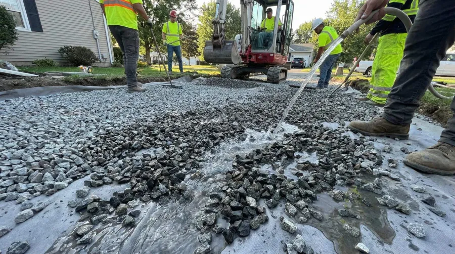 Drainage rock driveway installation showing water flowing through gravel