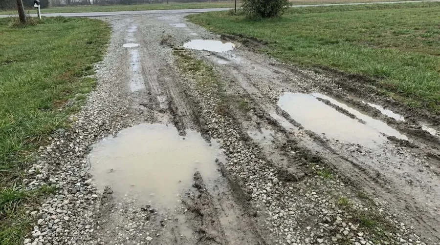 Uneven gravel driveway showing ruts and pooling