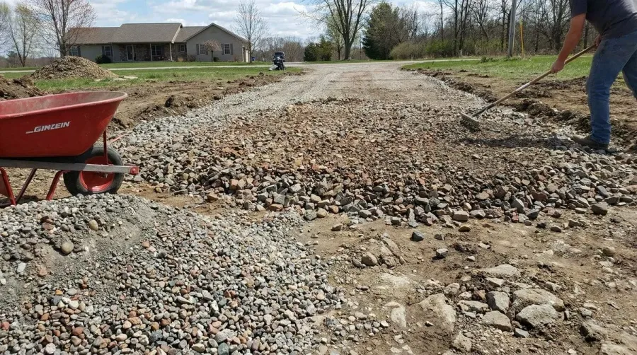 Base rock material being spread for driveway construction showing different sizes and textures