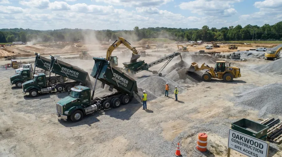 Professional gravel supplier delivering materials to a construction site with trucks and equipment