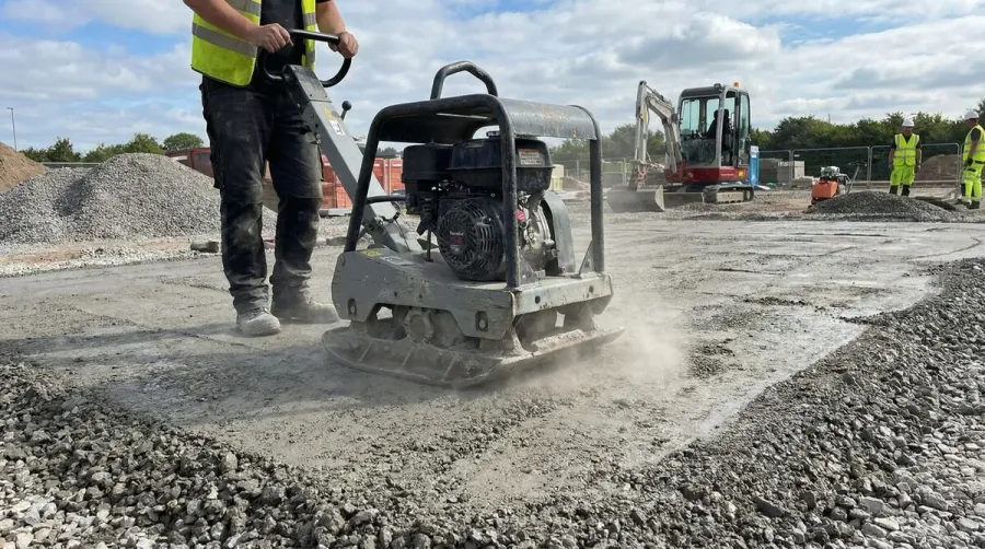 plate compactor being used on freshly spread crushed concrete, showing the finishing process