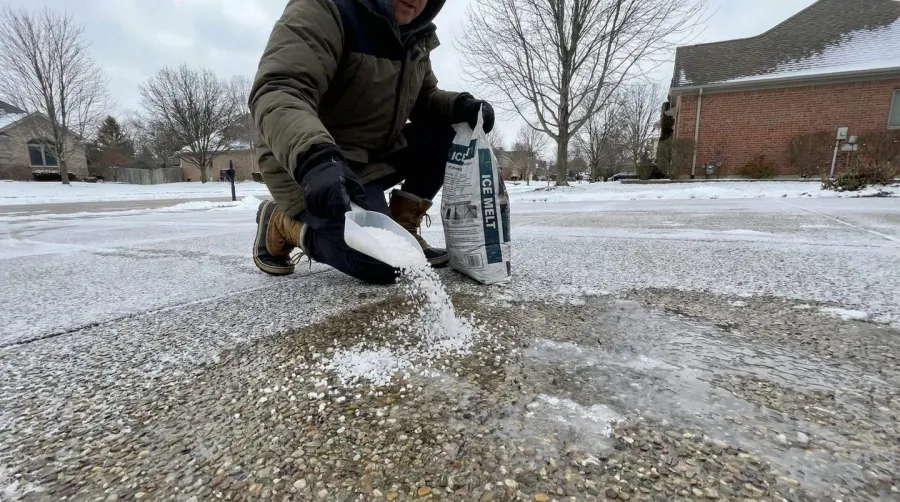 Salt being applied to icy aggregate driveway