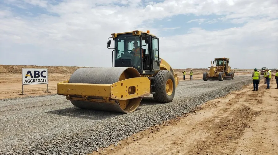Heavy equipment compacting ABC aggregate base course at construction site