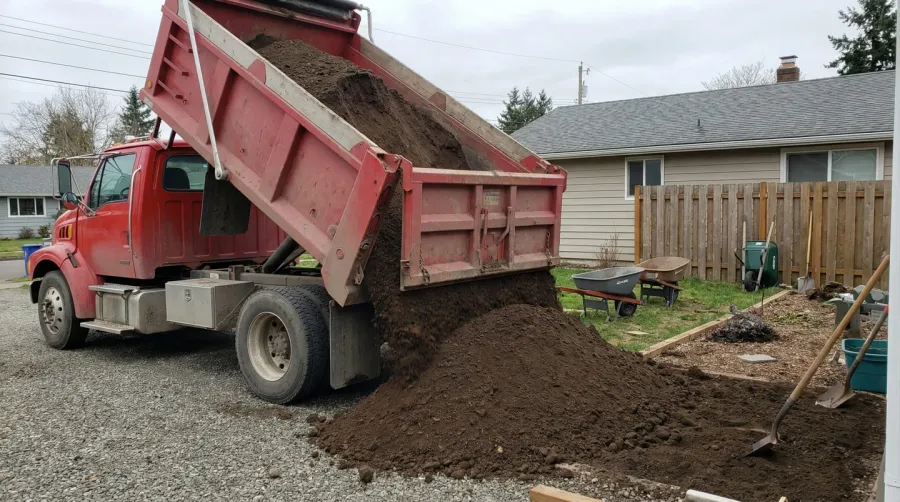 Clay loam delivery truck dumping soil at residential site