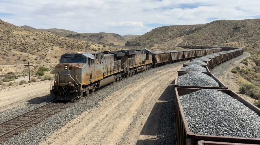 Freight train carrying gravel cars on railway tracks