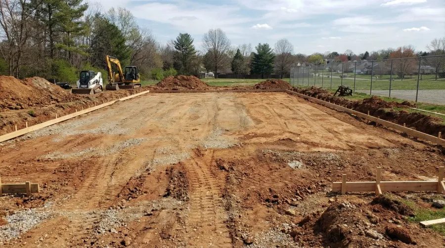 Excavated basketball court area being prepared for crushed stone installation