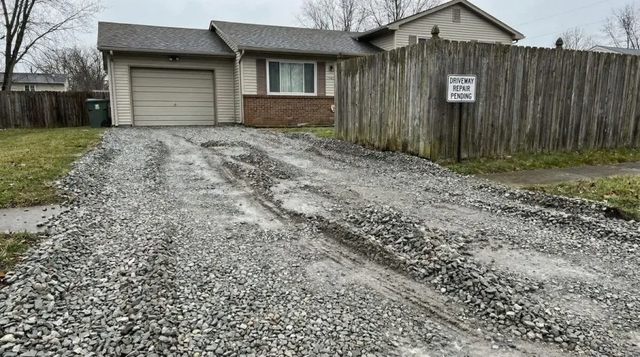 Loose gravel driveway before repair showing ruts and displacement