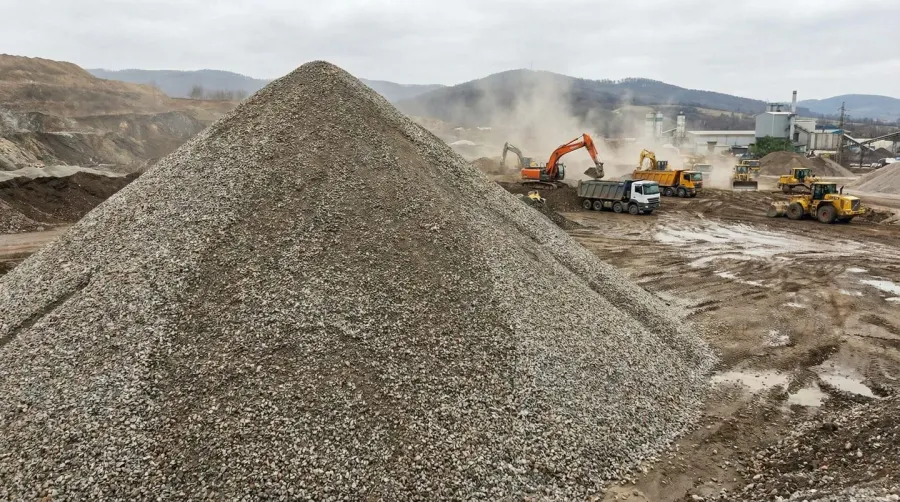 Large gravel pile with construction equipment in background