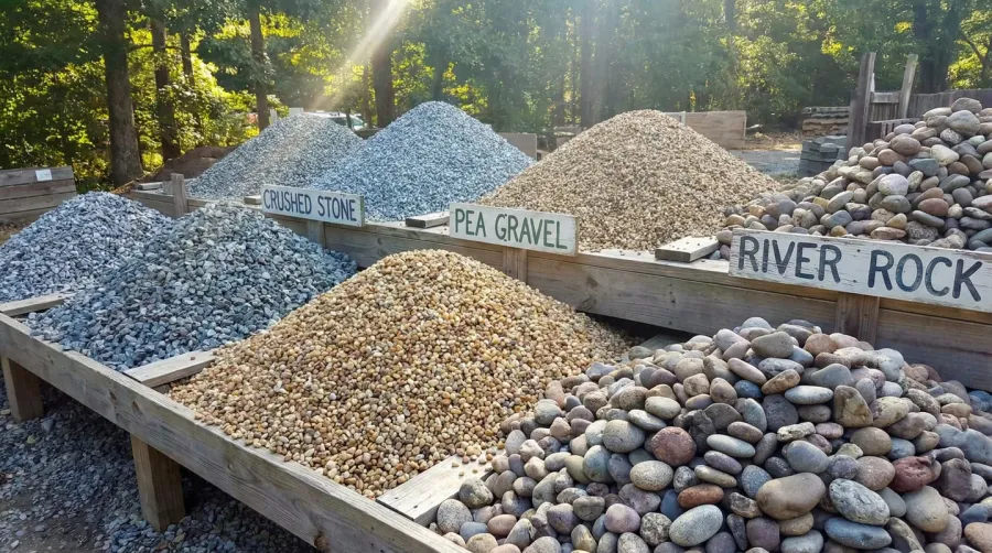 Various types of gravel displayed in piles showing different sizes and colors including crushed stone, pea gravel, and river rock