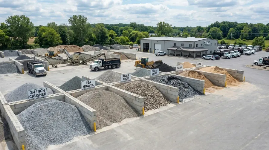 Professional gravel supplier facility showing organized piles of different gravel types with loading equipment
