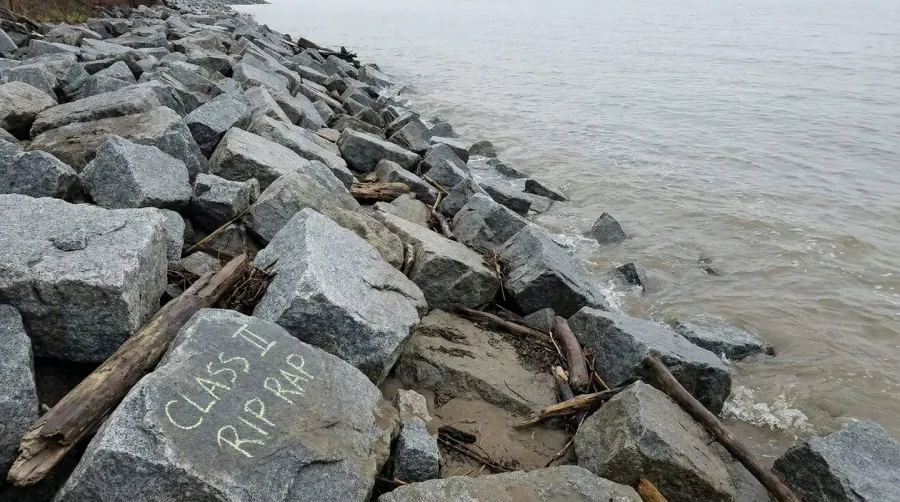 Class II rip rap boulders arranged along shoreline for erosion control, showing 18-26 inch diameter stones