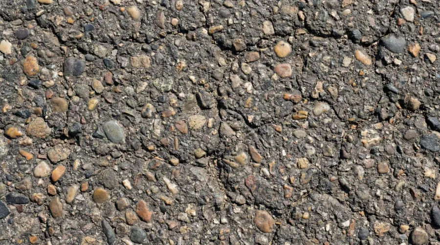 Close-up of pebbles embedded in asphalt with visible small cracks