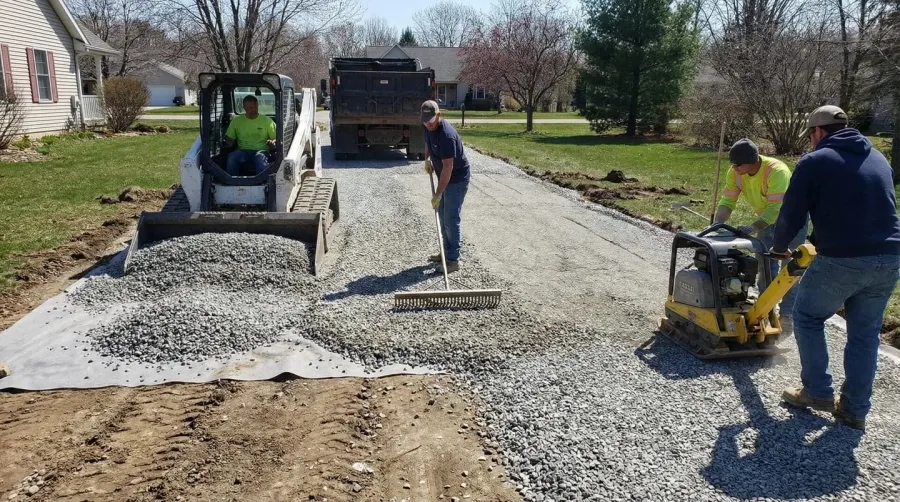 Gravel driveway being installed showing layers of stone, construction process with gravel being spread and compacted on residential driveway