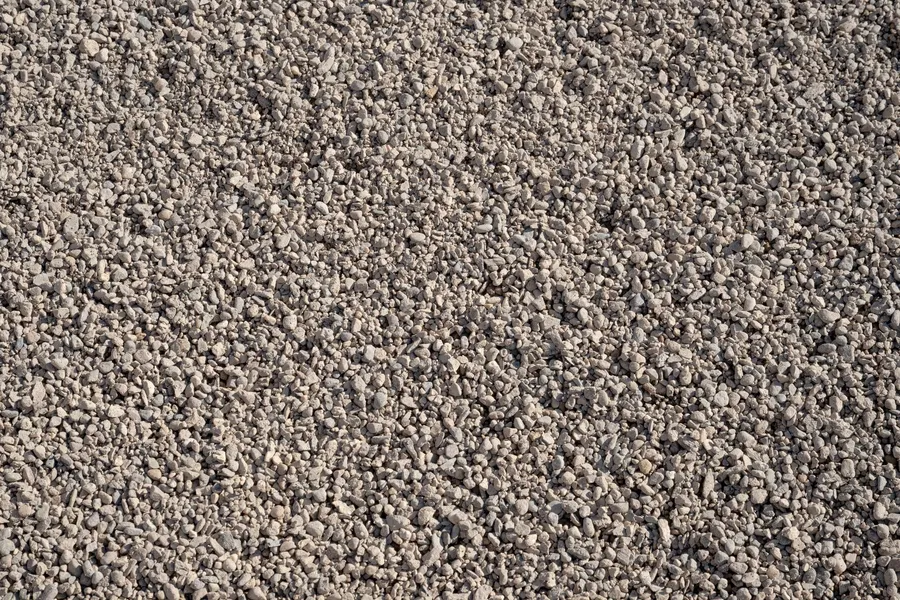 Handful of rounded 3/8 inch pea gravel held above a pile of pea gravel